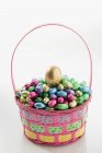 Basket of colorful shiny easter eggs on grey — Stock Photo