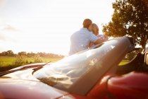 Rear view of couple sitting on electric sports car — Stock Photo
