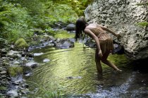 Teenage girl walking into stream — Stock Photo
