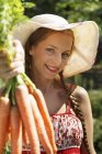 Портрет жінки середнього віку в саду, що тримає купу моркви — стокове фото