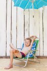 Garçon en maillot de bain dans la chaise de pelouse à l'intérieur — Photo de stock
