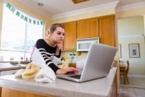 Femme utilisant un ordinateur portable dans la cuisine — Photo de stock