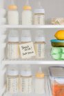 Bottles of breast milk on refrigerator shelves — Stock Photo