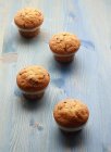 Four muffins on blue wooden table — Stock Photo
