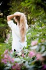Mujer de pie en arbustos de flores - foto de stock