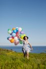 Uma menina correndo com balões no campo — Fotografia de Stock