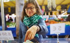 Young woman buying goods at market stall — Stock Photo