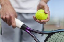 Uomo più anziano in possesso di palla da tennis e racchetta, colpo ritagliato — Foto stock