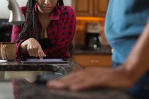 Couple adulte moyen utilisant une tablette numérique au comptoir de la cuisine — Photo de stock
