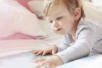 Head and shoulders of boy on bed lying on front looking at storybook — Stock Photo