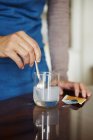Junge Frau mischt wasserlösliche Medikamente aus Beutel in Glas Wasser — Stockfoto