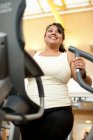 Woman using elliptical machine in gym — Stock Photo