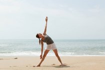 Женщина практикует йогу на пляже — стоковое фото