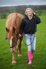 Девочка-подросток, ходящая лошадь в поле — стоковое фото