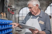 Cape Town, South Africa, elderly craftsman doing a count with pad in his hand — Stock Photo