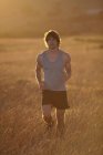 Чоловік біжить у високій траві на заході сонця — стокове фото
