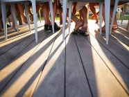 Muitas pernas sob as sombras de fundição de mesa — Fotografia de Stock