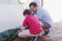 Pai e filho montando uma tenda juntos — Fotografia de Stock