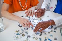 Senior woman and doctor with jigsaw puzzle — Stock Photo