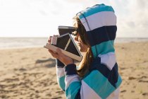 Mädchen mit Sofortkamera am Strand — Stockfoto