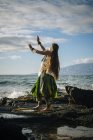 Mulher jovem hula dançando em rochas costeiras vestindo traje tradicional, Maui, Havaí, EUA — Fotografia de Stock