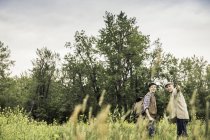 Uomo e ragazzo in piedi in erba alta guardando lontano puntando e sorridendo — Foto stock