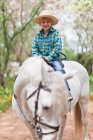 Усміхнений хлопчик верхи на коні в парку — стокове фото