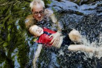 Пожилой человек учит внука плавать. — стоковое фото