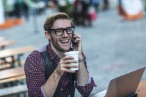 Giovane uomo d'affari chatta su smartphone al caffè marciapiede — Foto stock