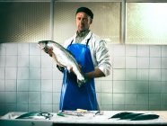 Fishmonger holding a salmon — Stock Photo
