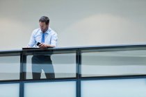 Businessman working on balcony using smartphone — Stock Photo