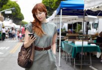Mujer adulta mirando el teléfono móvil en la ciudad - foto de stock