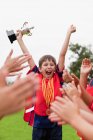 Діти вітають товариша по команді з трофеєм — стокове фото