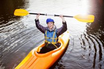 Kayaker sosteniendo el remo en un lago tranquilo - foto de stock