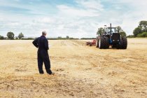 Фермер с видом на трактор на поле — стоковое фото