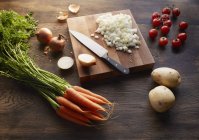 Carote fresche, patate e pomodorini con cipolle tritate sul tagliere — Foto stock