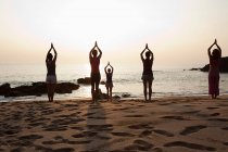 Women practicing yoga on beach at sunset — Stock Photo