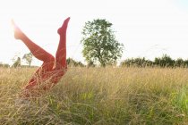 Female legs wearing red tights raised up on field — Stock Photo