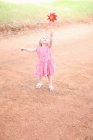 Девушка играет с вертушкой на грунтовой дороге — стоковое фото