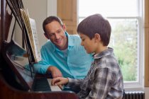 Отец учит сына играть на пианино. — стоковое фото