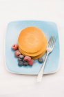 Berries and sugar on stack of pancakes — Stock Photo