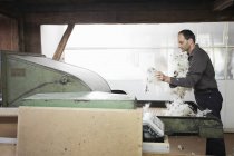 Hombre añadir vellón a la máquina en fábrica de lana - foto de stock