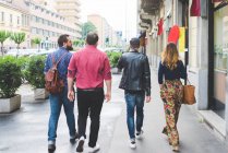 Group of friends walking on sidewalk together — Stock Photo