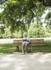 Senior mulher sentada no banco do parque leitura bíblia — Fotografia de Stock