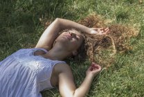 Девочка-подросток лежит на траве и улыбается — стоковое фото