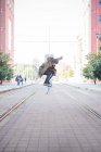 Jeune skateboarder masculin faisant du skateboard saut sur tramway — Photo de stock