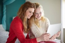 Dos chicas adolescentes mirando tableta digital en el dormitorio - foto de stock