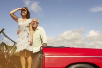 Senior couple with sports car, observing — Stock Photo