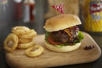 Burger und Zwiebelringe auf Holzbrett — Stockfoto