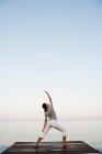 Giovane donna che fa yoga al molo — Foto stock